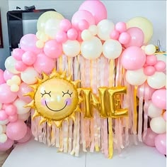 the balloon arch is decorated with pink, yellow and white balloons