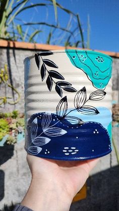 a hand holding up a ceramic cup with designs on it