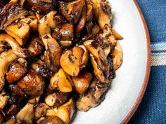 a white plate topped with cooked mushrooms on top of a blue and white table cloth