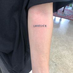 a person with a tattoo on their arm that says love sick in cursive writing