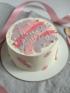 a birthday cake with pink and purple icing sitting on top of a white plate