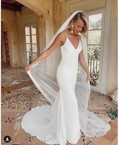 a woman in a white wedding dress is standing on the floor with her veil over her head