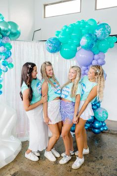 four girls standing in front of balloons and streamers