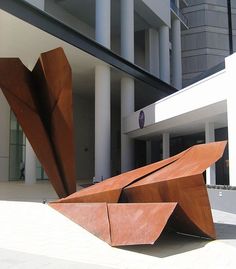 a large metal sculpture sitting in front of a building next to a tall white building