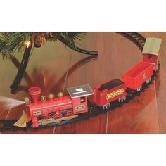 a toy train is on the tracks next to a christmas tree