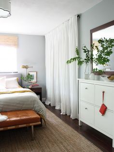 a bed room with a neatly made bed next to a dresser and a mirror on the wall