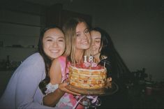 three girls smile as they hold a birthday cake