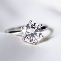 a close up view of a ring with a diamond in it on a white surface