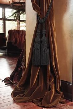 a brown curtain with tassels hanging from it's side on a wooden floor