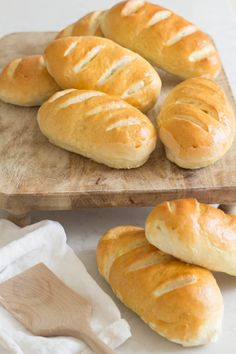 bread rolls on a cutting board next to a wooden spatula