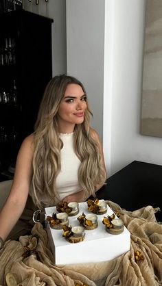 a woman sitting at a table with cupcakes on it