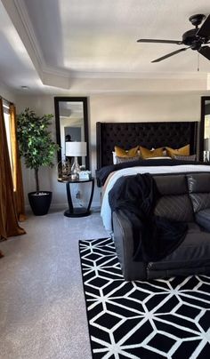 a black and white bedroom with a bed, couch, lamps and mirror on the wall