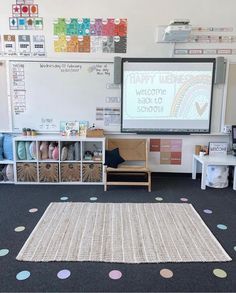 a classroom with a large white board and polka dot rugs on the floor in front of it