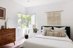 a bedroom with white brick walls and wooden furniture, along with a black headboard