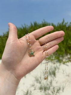 This coastal inspired necklace features a white and gold chain, and is finished with a colorful enamel starfish charm in the color of your choice. This 16 inch necklace closes using a gold lobster claw.  If you do decide to wear your jewelry to the beach, consider slipping it off and stowing it in a secure place before you head into the water. If you like this, you'll love the matching earrings! Check it out here on my shop! https://www.etsy.com/listing/1724960232/coastal-inspired-starfish-earrings-beach?click_key=8ccdb0f39da7ad646401ef427358bf5007cf2d4e%3A1724960232&click_sum=63d9e728&ref=shop_home_active_1 All orders will be packaged in a small box along with bubble packaging for safest of travels to you! Thank you for supporting my small business! - Olivia from The Sandy Poppy <3 Starfish Necklace With Lobster Clasp For Vacation, Starfish Charm Strand Jewelry For Gift, Starfish Charm Strand Jewelry Gift, Starfish-shaped Necklace With Pearl Charm For Gift, Beach Star Charm Necklace, Adjustable Green Starfish Jewelry, Starfish Shaped Beaded Necklaces For Gift, Starfish-shaped Beaded Necklace For Gift, Starfish Shaped Beaded Necklace For Gift