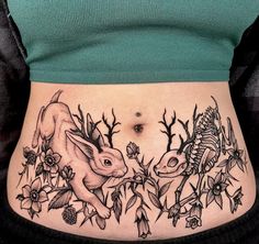 a woman's stomach with an animal and flowers tattoo on the side of her belly