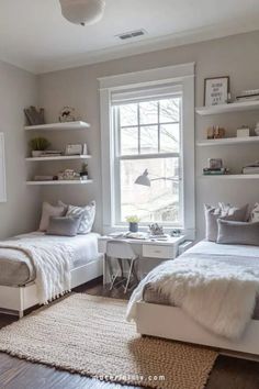 two twin beds in a bedroom with white walls and shelves on the wall above them