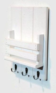 a white wall mounted shelf with hooks on it