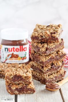 chocolate peanut butter granola bars stacked on top of each other with nutella in the background