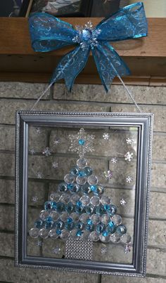 a christmas tree made out of glass balls hanging on a wall with a blue bow