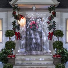 an entrance decorated for christmas with potted plants and poinsettis on the steps