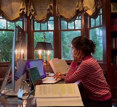 a woman sitting at a desk in front of a laptop computer with books on it