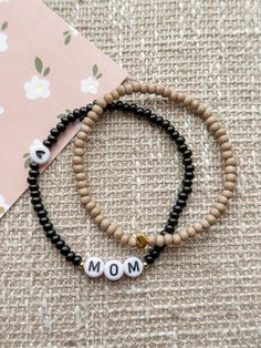 two beaded bracelets with the word mom written in white and black beads on them