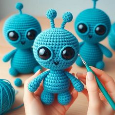 a crocheted blue toy sitting on top of a table next to balls of yarn