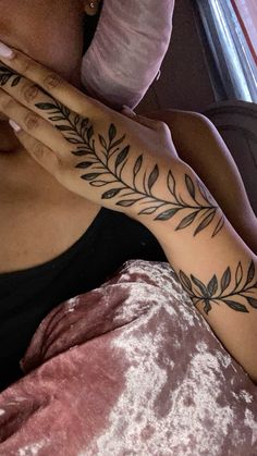 a woman laying on top of a bed with a tattoo on her arm and hand