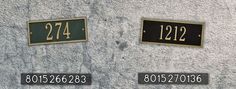 two black and gold plates with numbers are on the side of a gray stone wall