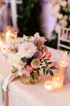 a table topped with lots of pink flowers and gold vases filled with white wine glasses