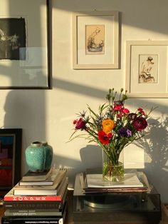 a vase filled with colorful flowers sitting on top of a wooden table next to books