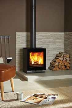 a wood burning stove in a living room next to a pile of logs and a chair