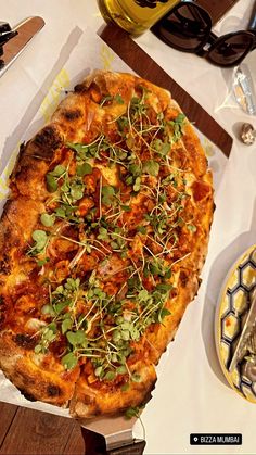 a pizza sitting on top of a wooden cutting board next to a knife and fork