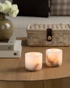 two white candles sitting on top of a wooden table