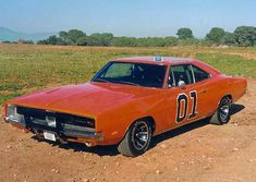 an orange muscle car sitting in the dirt