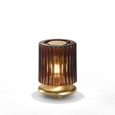 a small brown candle holder on a white surface with light coming from it's top