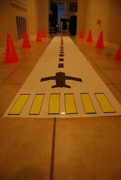 a white and yellow road sign sitting on top of a floor next to orange traffic cones