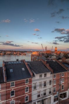 the city skyline is shown at sunset with clouds in the sky and water behind it