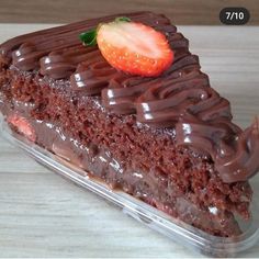 a piece of cake with chocolate frosting and a strawberry on top is sitting in a plastic container