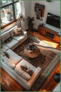 A cozy living room with a large sectional sofa, a round wooden coffee table, a TV on the wall, and a bookshelf beneath a large window. Low Living Room, Sofas In Living Room, Neutral Modern Living Room, Cozy Sofas, Two Sofas, L Couch, Cozy Sofa, Dream Living, Furniture Layout