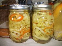 two mason jars filled with pickled onions and orange peels, sitting on a table