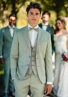 a man wearing a suit and bow tie standing in front of other men