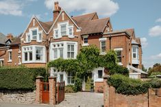 a large brick house with white windows and ivy growing up the side of it's walls