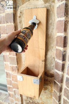 a person holding a beer bottle in front of a brick wall with a door handle