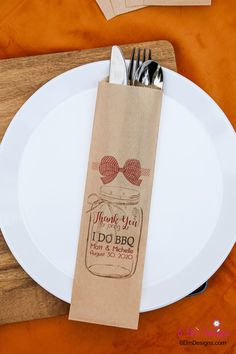 a white plate topped with a paper bag filled with utensils