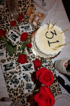 a cake with the number twenty one on it sitting next to roses and wine glasses