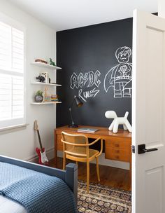 a bedroom with chalkboard on the wall and a desk in front of an open door