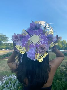 a woman wearing a purple hat with flowers and butterflies on it's head in the grass