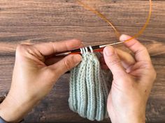 someone is knitting something on a wooden surface